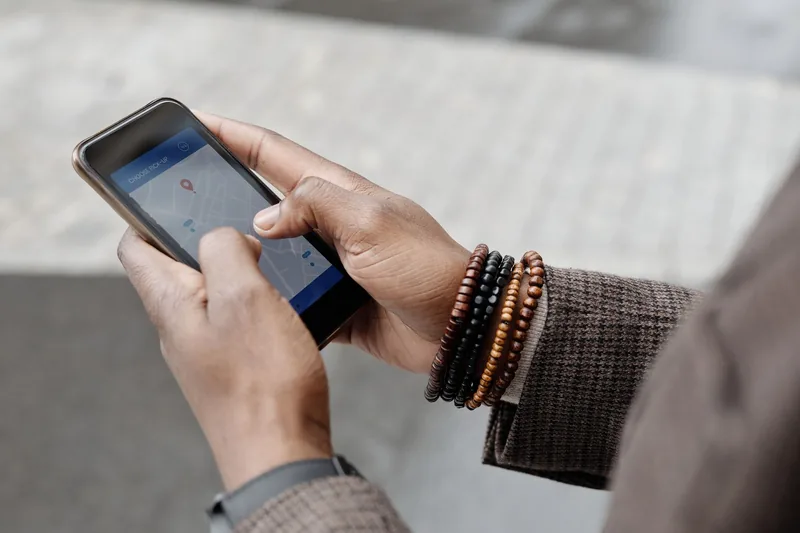 Close-up of hands holding a phone with a map and location pin on screen