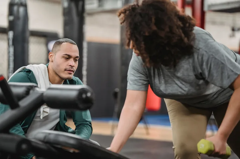 A personal trainer coaching a gym member through an exercise