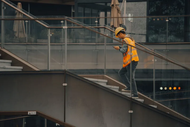 Contractor in a safety vest checking his phone between jobs on site
