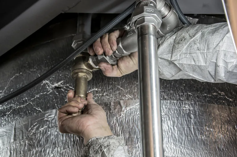 Plumber fitting pipes under a sink during a service call