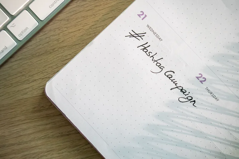 A handwritten social media campaign note in a weekly planner next to a keyboard