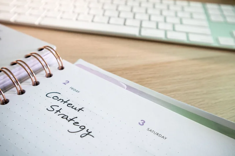 A content strategy plan written in a weekly planner beside a keyboard